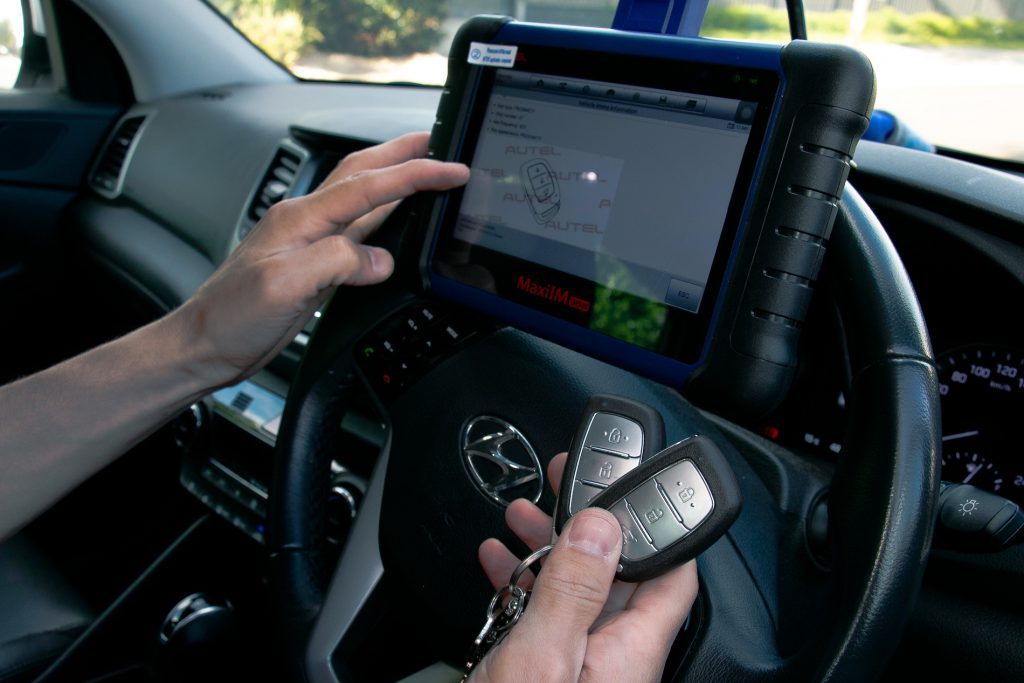 Hyundai-sleutels in de hand terwijl ze met een programmeertablet via de diagnoseaansluiting worden ingeleerd