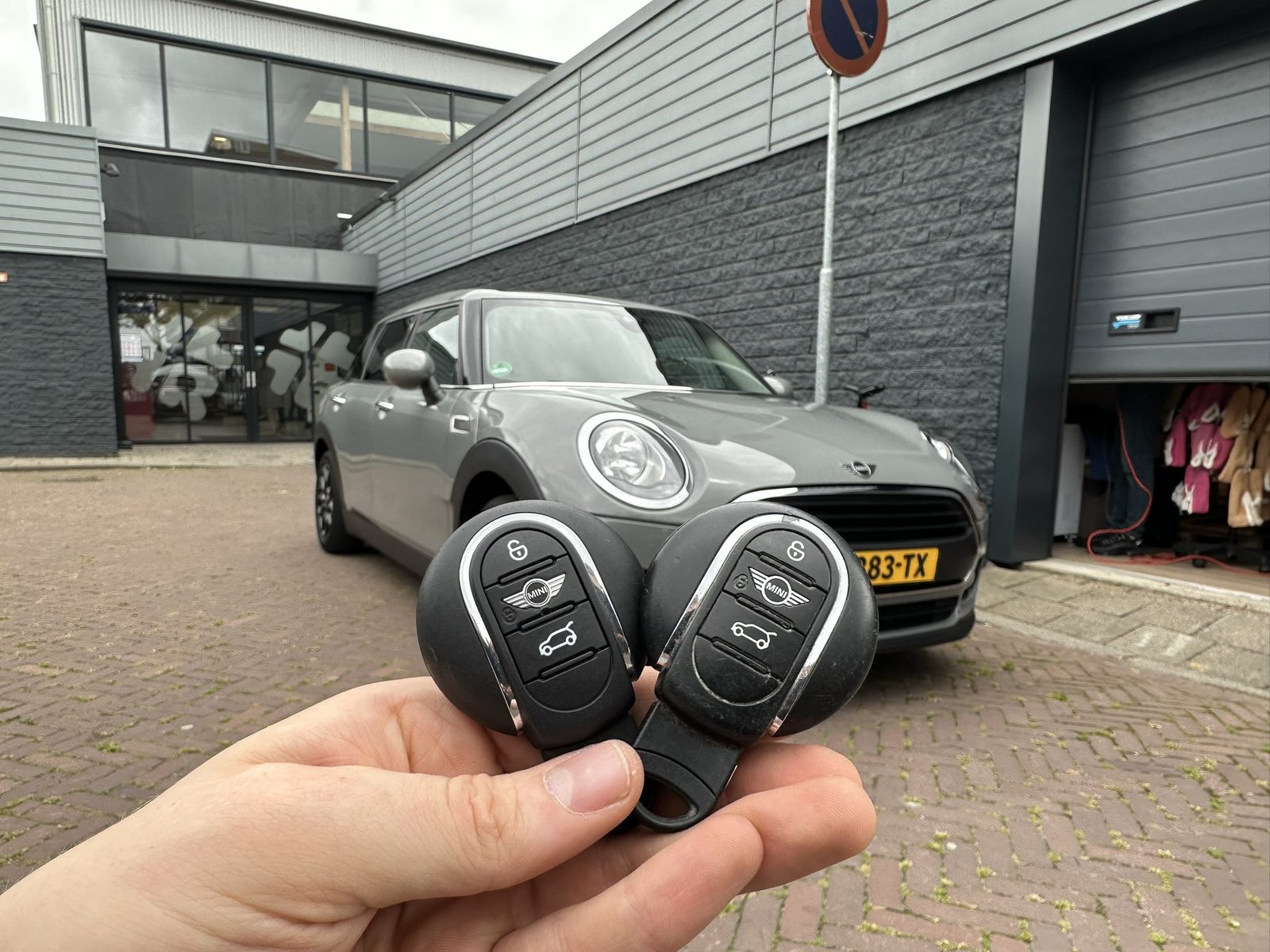 Twee Mini-smartkeys in de hand, met de Mini Clubman op de achtergrond