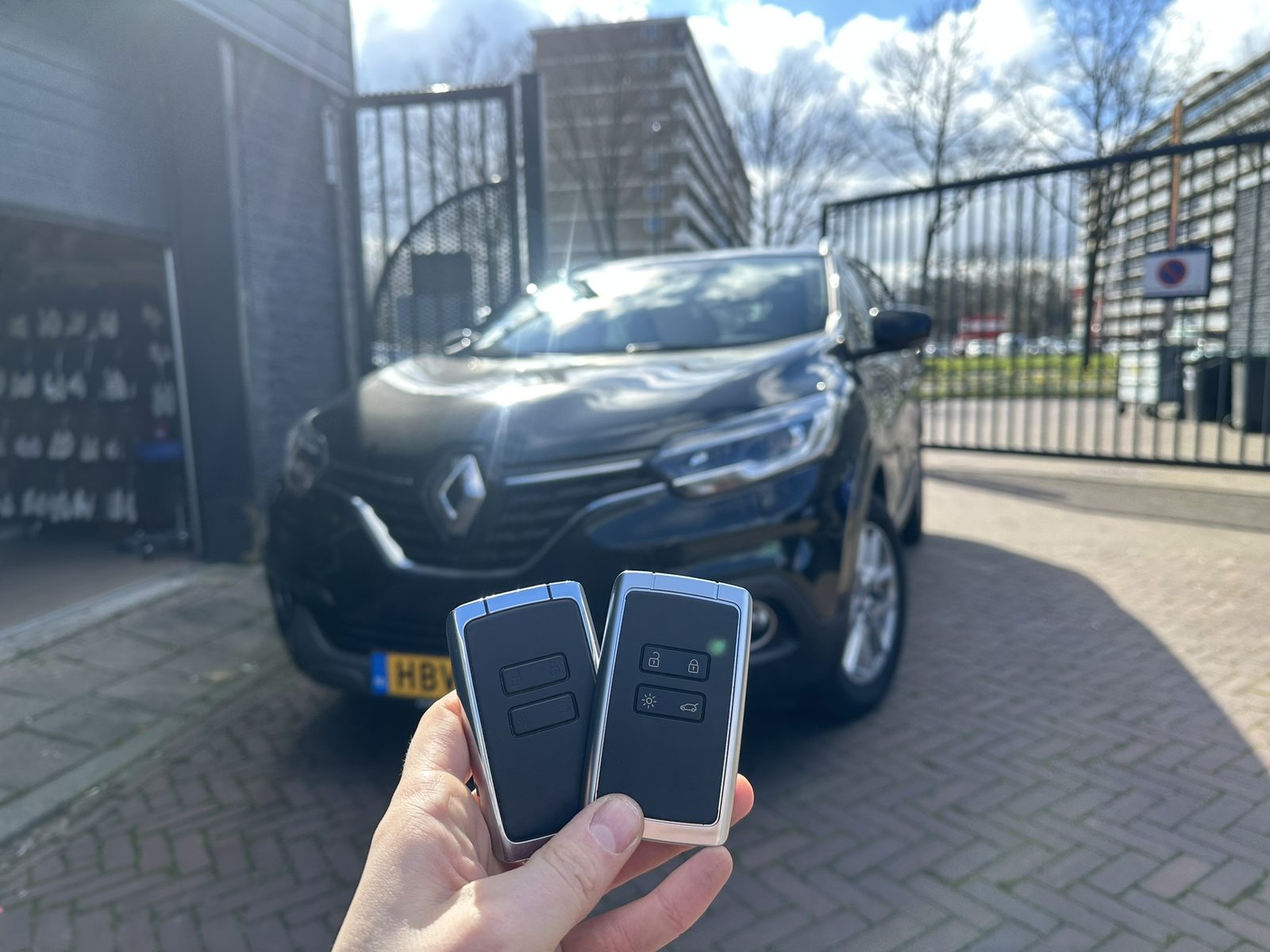 Twee Renault-sleutelkaarten in de hand, met de Renault Kadjar op de achtergrond